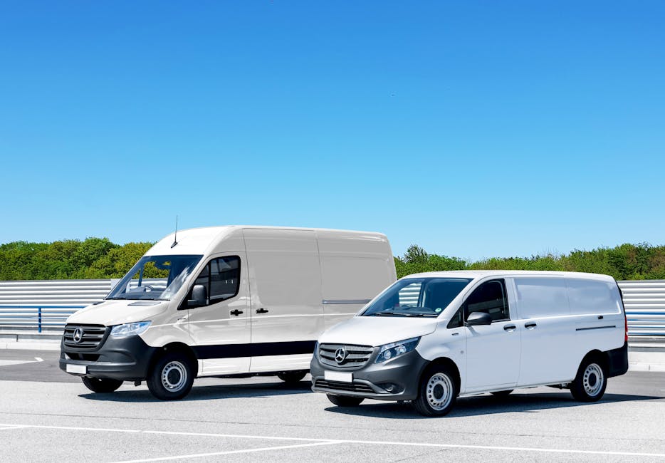 Two white Mercedes-Benz vans parked side by side on a paved roadside near Millfields Park under a clear blue sky; the larger van on the left is a high-roof panel van with a sliding side door, while th